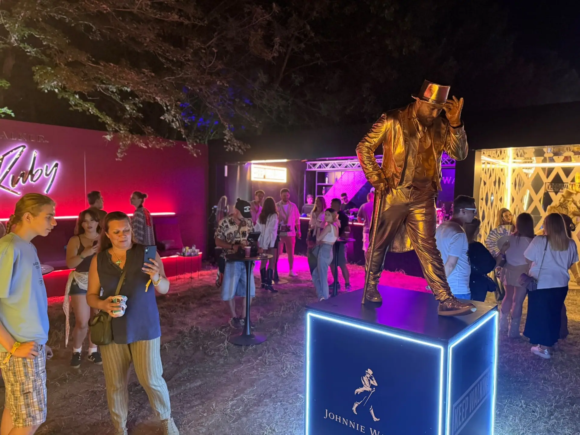 A living statue in a gold suit with a cane — the Johnnie Walker image, brought down among the Nostalgia crowd.